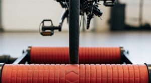 Smart bike rollers with Bluetooth connectivity paired to smartphone displaying cycling training app interface and power data