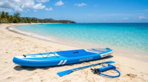 Blue inflatable paddle board and pump resting on a sunny sandy beach.
